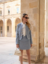 A lady wears a tweed suit.